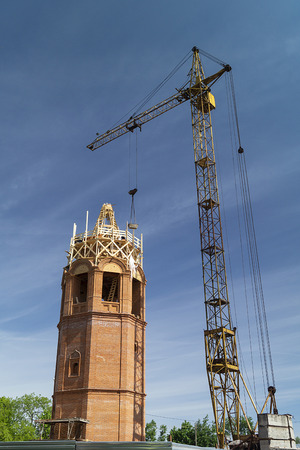 The Construction to bell towers in city Vyazniki,Russia. Building from red brick on background blue skyの写真素材