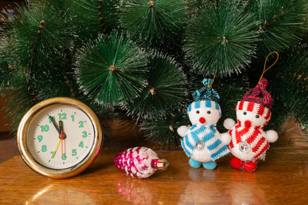 Round watch with toy on wooden table under fir tree in cristmas at night