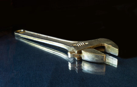 The Wrench rests upon glass table on black background. The Instrument for fastening the details.
