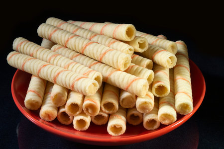 The Sweet sticks with stuffing in red plate on black background. Dessert to tea on black background