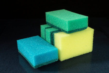 The Sponge for dishwashing on glass table on black background. The New facility hygiene. Porous and...