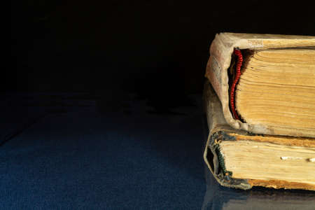 Aging book rests upon glass table with reflection. Subjects on black background close-upの写真素材