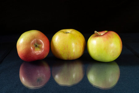 The Ripe apple to rest upon table with reflection. Products of the feeding on black background