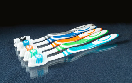 The Set of the toothbrushes on glass table with reflection Instruments for hygiene on black...