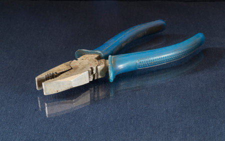 Iron pliers lie on a table with a reflection. Locksmith tools on a black background