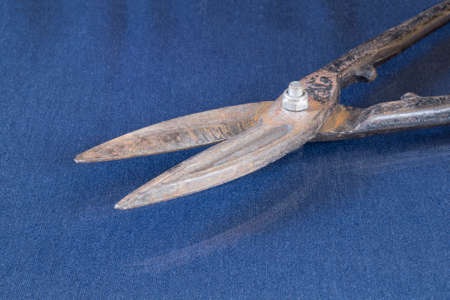 Rusty metal scissors lie on the table with the reflection. Locksmith tools on a blue backgroundの写真素材