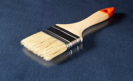 Paint brush with wooden handle on the table. Tools on a blue background with reflection