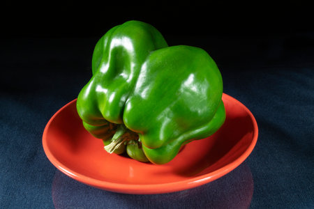 Green pepper in a red plate on the table. Food products on a black backgroundの写真素材