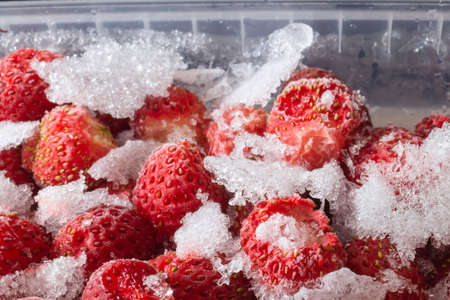 Frozen strawberries in a plastic container. Beautiful food backgroundの写真素材