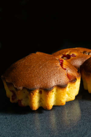 The Sweet fruit cakes are with berry to rest upon glass table.Home baking on black backgroundの写真素材
