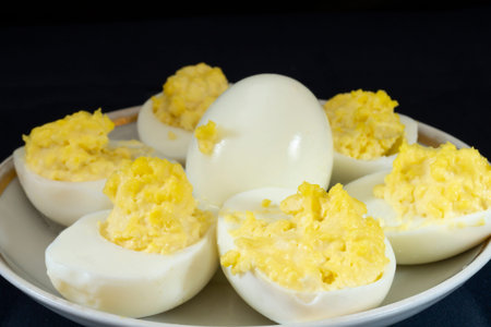 Stuffed egg yolk with mayonnaise in a white plate. food on a black background