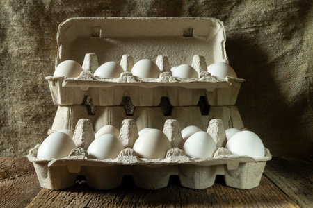 Still life with eggs in ecological cardboard packaging. Food on a dark background.