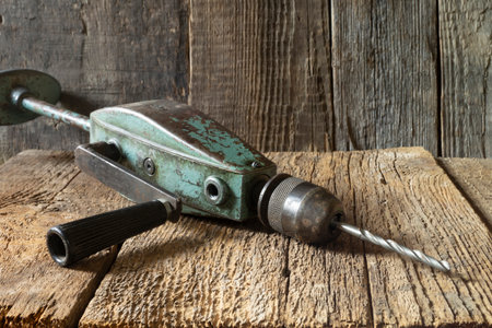A metal tool for drilling holes. An old object on a background of wooden boardsの写真素材