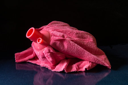 A pink microfiber mop head on a glass table. Household items with reflection on a black backgroundの写真素材