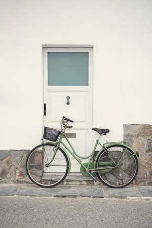 Vintage green bicycle resting on a white wallの写真素材