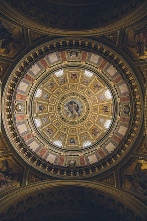 Interior of Roman catholic church St. Stephen's Basilica dome. Richly decorated ceiling with painted scenes and gold details.のeditorial素材