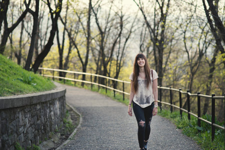 Attractive young woman enjoying her time walking outside in park . Caucasian girl with long brown hair smiling.の写真素材