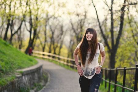 Attractive young woman enjoying her time walking outside in park . Caucasian girl with long brown hair smiling.の写真素材