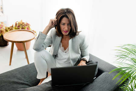woman siiting on sofa at home working relaxed with laptopの写真素材