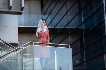 Mixed race young woman wearing hijab on a built structureの写真素材