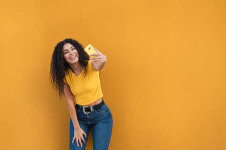 Funny mixed race girl taking selfies pictures with her smartphoneの写真素材