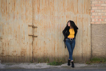 Attractive young woman wearing black jacket and blue jeans on the streetの写真素材