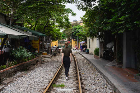 woman walking on the railroad tracks in an urban environmentの写真素材