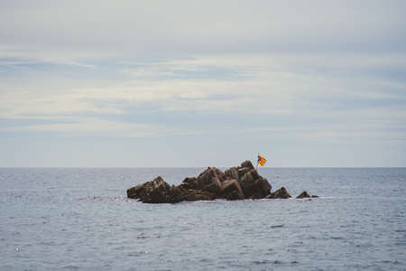 a nationalist flag flies on a desert islet in the middle of the mediterranean seaの写真素材