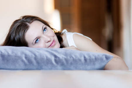 A close up of a young woman laying on the bed with a pillowの写真素材