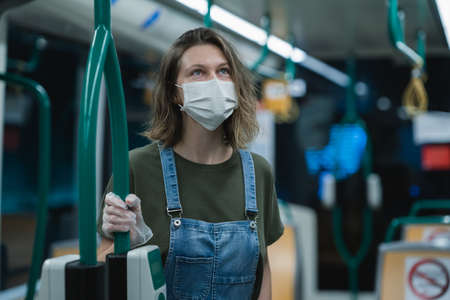 Woman wearing surgical protective mask and gloves in a public transportationの写真素材