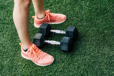 photography of a sportswoman's feet next to dumbbells on the grass floorの写真素材
