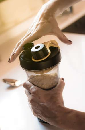 girl's hands with vitiligo making a protein shake after sportの写真素材