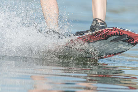close-up of a boy's legs practicing wake boarding on a riverの写真素材