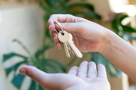 one hand giving the keys of a house to another hand. concept handover of keysの写真素材