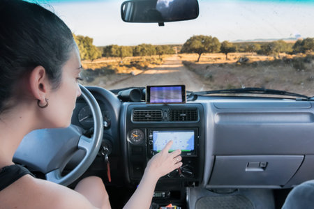 young woman calculating a route in the car navigator. lonely dirt road