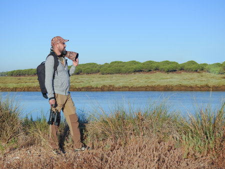 young hipster man with a beard in the field carrying a photographic equipment with a reflex camera...