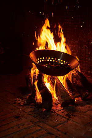 chestnuts roasting over the fire in a typical frying pan over a fireplace. rural concept and village traditionの写真素材