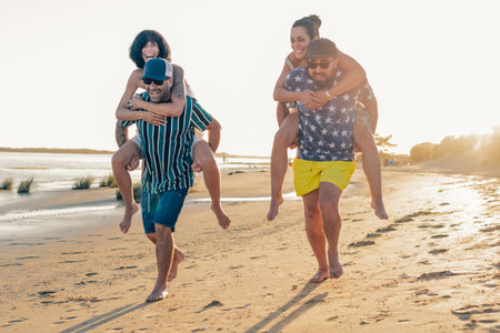 group of young friends on vacation having fun together on the beach. Group of friends doing a race on top of each other. Togetherness and leisure activity lifestyle concept.の写真素材