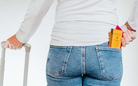 Young woman with her suitcase prepared to travel after the global pandemic    taking out her international passport and her vaccination certificate .の写真素材
