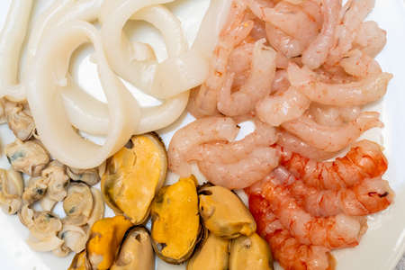 Macro photograph of a clean seafood plate ready to make a paella. squid, clams, mussels and prawns. healthy food conceptの写真素材