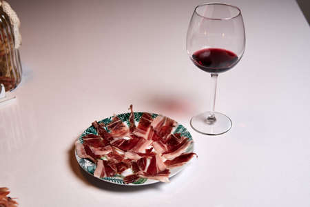 plate of typical Spanish Iberian ham cut by hand with a glass of Rioja red wineの写真素材