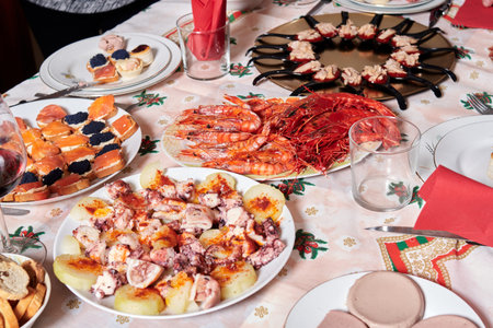 table set up for Christmas dinner with salmon and caviar canapes, Galician octopus dish, teaspoons...