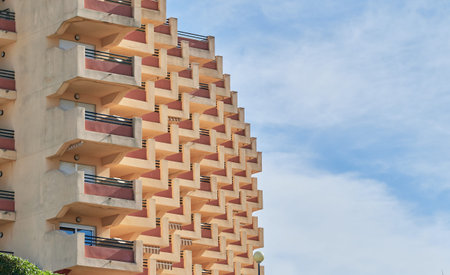 stair stepped vacation building with balconies and windows with blue sky and clouds backgroundの写真素材