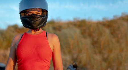 Young smiling biker woman wearing red tank top and black motorcycle safety helmet. copy spaceの写真素材