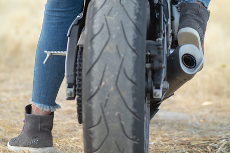 rear view of the wheel of a road motorcycle. feet of a biker woman wearing safety boots for riding a...
