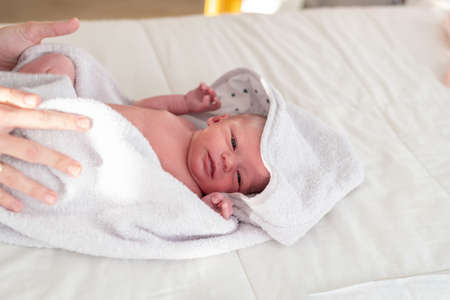 hands of a mother drying her newborn baby with a soft towel after giving her a warm bath following her bedtime routineの写真素材