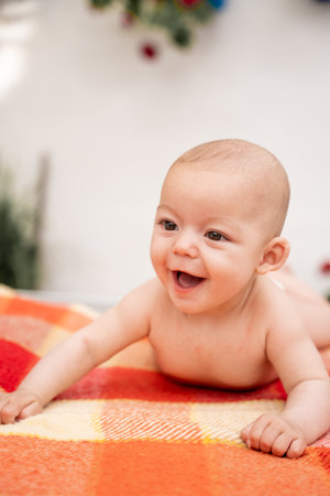 Close-up portrait of a laughing baby with his mouth open lying on his back on a plaid blanket.の写真素材
