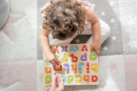 overhead view of a girl interacting with her mother sitting on the floor of her room with a wooden...