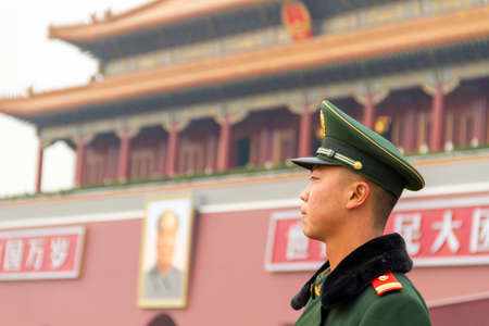 Beijing, China - November 21 2019: Young Chinese soldier guards the Gate of Heavenly Peace. On the sides of Mao's portrait is written "Long live the People's Republic of China and long live the great unity of the peoples of the world."のeditorial素材