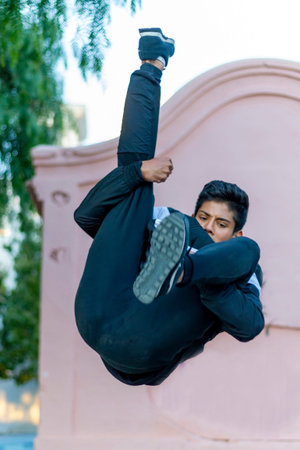 Active Latino young man jumping in action. Extreme sport activity, parkour outdoor free running or healthy lifestyle conceptの写真素材